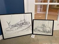 Two Scott Kennedy signed sailboat artworks in black frames, one larger titled COURAGEOUS, displayed against a wall.