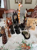 Overview of multiple wooden and ceramic giraffe figurines arranged on table, featuring different sizes and styles.