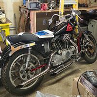 Left side view showing tank, engine, exhaust and seat