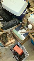 Photo showing white portable cooler, black hard tool case, cardboard boxes filled with papers and records, paint brushes, and miscellaneous items