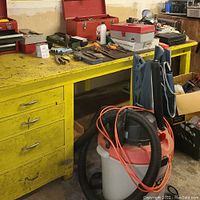 Yellow workbench with assorted hand tools and Rigid Shop Vac in front