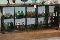 Wide view of wooden cubical storage unit with various glass and decorative items inside compartments to show scale and structure.