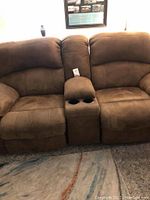 Full view of brown double recliner sofa with two seats, center console with cup holders, in living room setting.