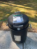 Front view of Brinkmann Smoke'N Grill smoker showing lid with handle and thermometer