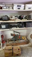 Shelf with multiple electronic devices including a Dayton permanent magnet DC motor, Sears Craftsman miter saw mounted on wooden base, and other electronic equipment.