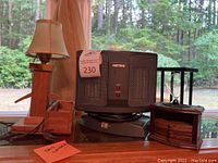 Patton electric heater, wooden lamp with pinkish fabric shade, wooden box with drawer.