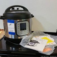 Front view of Instant Pot Duo Nova pressure cooker with digital control panel and auction lot label.