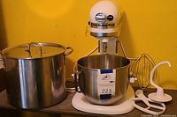 KitchenAid mixer with attached 5 quart stainless steel bowl and 12 quart stainless steel stockpot beside it.