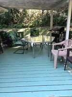 Patio setting showing the hexagon glass top table and 8 chairs, 2 iron with cushions and 6 plastic/metal chairs