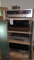 Full front view of stereo receiver, record player, VHS player, and CD player stacked in a shelf