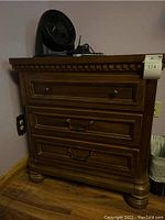 Full view of the wooden nightstand showing front with all three drawers and decorative molding on top.