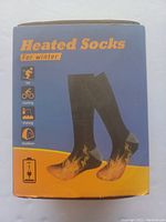 Photo of the packaging front showing heated socks for winter with icons indicating use for skiing, cycling, fishing, and outdoor activities.