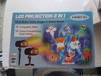 Box showing LED Projection 2 in 1 with Halloween themed slides and ocean wave colors.