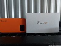 Photo showing orange Roam Fi WiFi hotspot device alongside its white branded box.