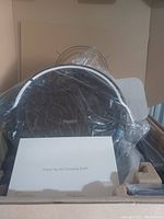 Robit robot vacuum cleaner partially wrapped in plastic with user manual in front, inside cardboard box packaging.
