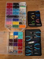 Plastic beads sorted by color and size in compartmentalized plastic containers alongside jewelry making pliers in black cases.