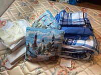 Full view of the bed sheet set folded, two lighthouse-themed tapestry throw pillows, and lace curtains all placed on a floral mattress.