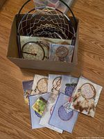 Box of assorted dream catchers mostly new and unopened in plastic packaging and backing cards