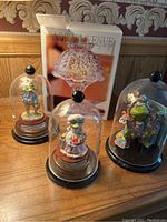 Photo showing three Leonardo frog figurines in glass domes and the boxed Fifth Avenue crystal candle lamp in the background
