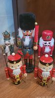 Front view of all five nutcrackers showing size and color variations, red nutcracker missing paint on hat clearly visible