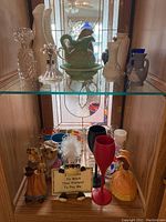 Shelf with various collectible decor items including figurines, mugs, glasses, and pitchers.