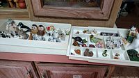 Two trays of assorted vintage miniature animal figurines including owls, dogs, cats, birds, and other small animals in natural colors.