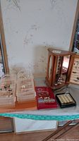 View of multiple pierced costume earrings on display holders next to red jewelry cleaner cloth and small black ring box