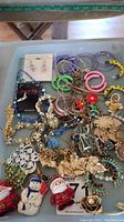 Top view of various costume jewelry pieces including bracelets, earrings, rings, and festive pins on a table