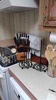 Cutlery set in wooden block, paper towel holders on stove and countertop.