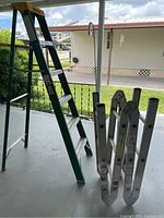 Green Warner 12 foot step ladder and aluminum Werner multi-position folding ladder shown deployed in partially open positions.
