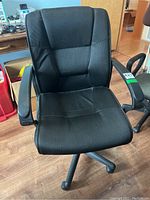 Front view of a black fabric office chair showing padded segmented backrest and seat, with armrests on both sides.