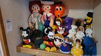 Full lot showing assortment of vintage plush and plastic toys including Raggedy Ann dolls, Mickey Mouse figures, Pillsbury Doughboy and Doughgirl, Orange Bird, Crayola plush and other dolls.