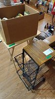 View of folding wooden TV tray next to metal and faux wood shelf with boxes on and around them