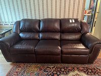 Front view of the dark brown leather reclining sofa showing overall shape and 3-cushion seating.