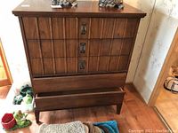 Front view of vintage five drawer tall boy dresser with open lower drawers and geometric drawer fronts with metal pulls, showing wood finish and condition.