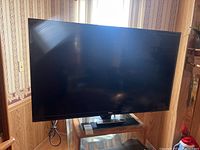 Front view of the RCA 49 inch flat screen TV on a wooden stand in a room.