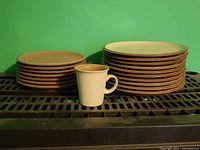 Photo showing stacked sets of plates and one mug in front, viewed from left side.