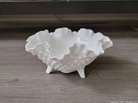 Side angle photo showing the ruffled shape and hobnail texture on white opaque glass with three feet