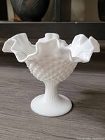 Front angle view of the white milk glass pedestal dish showing the ruffled rim and hobnail pattern.