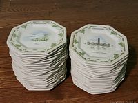 Two stacks of octagonal Johnson Brothers Christmas plates from 1983 and 1984 depicting Canadian House of Parliament and Niagara Falls.