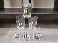 Photo showing all 6 colorful mid-century modern sailboat shot glasses arranged on steps.