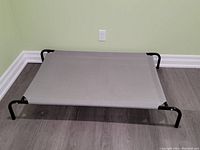 View of the full elevated dog bed showing black metal frame and gray mesh fabric surface