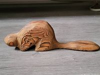 Full side view of the wooden beaver sculpture showing its length and wood grain patterns.