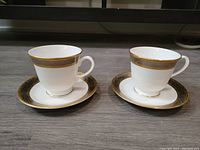Pair of Royal Worcester Contrast cups and saucers showing gold and silver decorative banding.