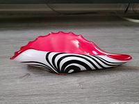 Side view showing the red interior and black and white striped exterior of the conch shell sculpture.