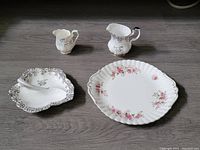 Overview photo showing all pieces: two creamers, the 25th Anniversary divided dish with serving spoon, and the Lavender Rose cake plate.