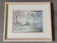 Framed vintage print of an outdoor scene with flowering tree, house porch, and laundry line, shown fully in the frame.