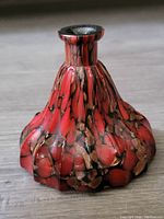 Front view of flared, scalloped base vase with red, black, and gold flecks