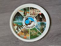 Full view of the round tin tray showing the color collage of animals and central logo.
