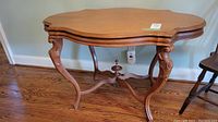 Full view of antique wooden table showing scalloped shaped top, finished surface, and carved cabriole legs